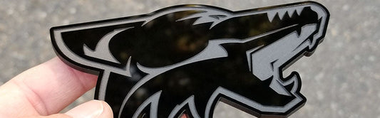 Gloss black coyote head badge with matte engraved detailing made from UV rated acrylic held outdoors.
