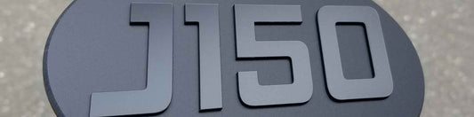 Oval J150 emblem in matte black with raised satin black lettering and beveled edge.